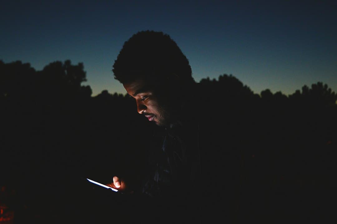 Ein Mann prüft in einem dunklen Raum das Display seines Smartphones