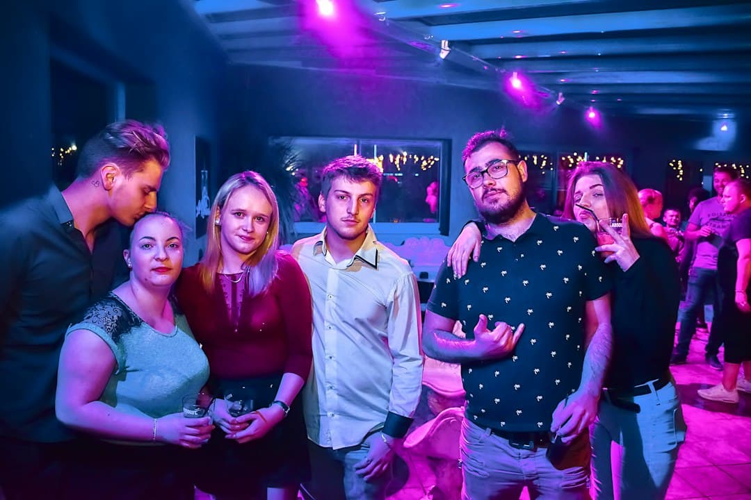 Eine Gruppe von Freunden posiert gemeinsam auf einer schwach beleuchteten Party