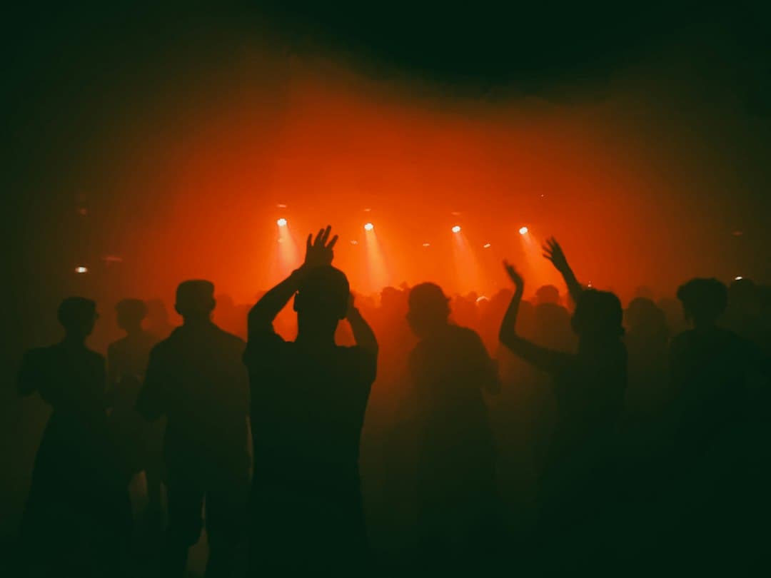 Volle Tanzfläche vor der DJ-Bühne, in tiefgrünes Licht getaucht, während einer Clubnacht
