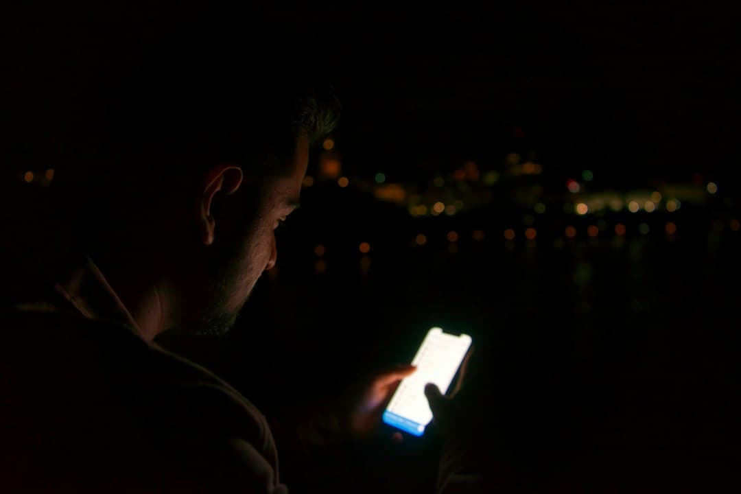 Ein Mann schaut in einem dunklen Raum auf sein Smartphone